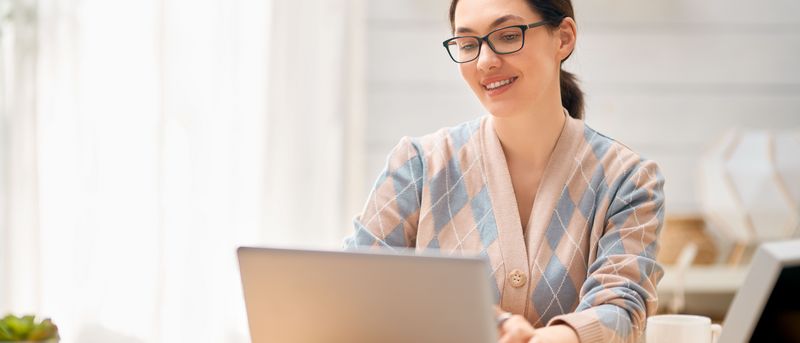 Eine Frau sitzt am Laptop an ihrem Schreibtisch.