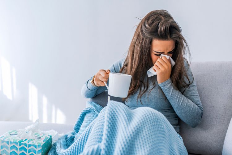 Eine junge Frau die ständig erkältet ist durch zu viel Stress.